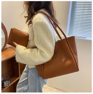 Close-up of caramel PU leather tote bag with matching zippered pouch on indoor set