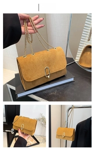 Close-up of brown suede shoulder bag featuring a gold chain strap and metal clasp detail