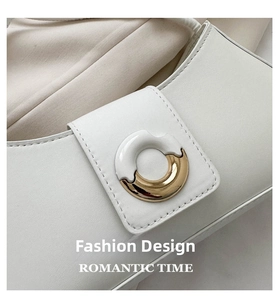 Detailed close-up of cream white leather handbag featuring a gold and white round metal buckle