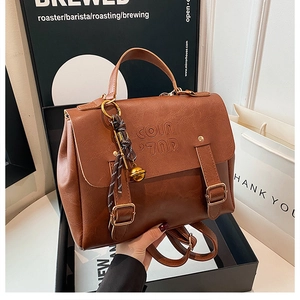 Detailed view of the brown textured leather backpack showing the buckle and embossed logo