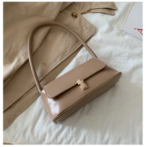 Gros plan du sac baguette kaki avec boucle dorée sur tissu blanc et fond de trench-coat
