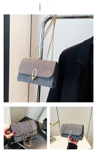 Detailed close-up of grey suede square bag with golden U-shaped buckle and chain strap