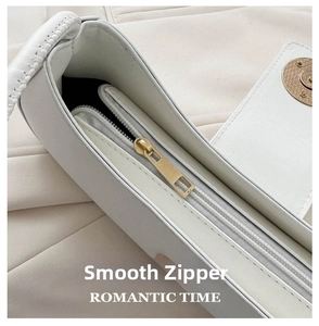 Close-up of golden metal zipper and smooth texture on white leather shoulder bag