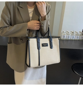 Détail d'un grand sac cabas en toile avec garnitures en cuir noir et anses sur un modèle