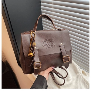 Close-up of brown textured leather bag with gold buckle detail and embossed logo