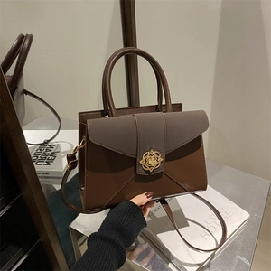 Two-tone leather handbag with golden floral clasp and top handle for commuting
