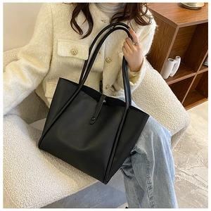 Minimalist black faux leather tote bag showcased in a stylish lifestyle setting