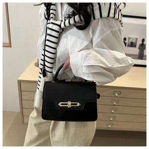 Detail of black pebbled leather crossbody bag with elegant gold metal twist-lock closure