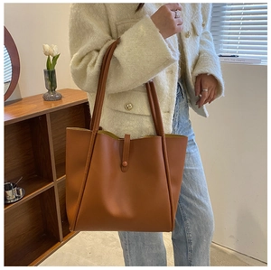 Detailed view of caramel brown tote bag featuring smooth faux leather texture and strap buckle
