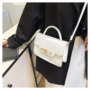 Detailed view of white crossbody bag featuring lizard texture and gold metal lock detail