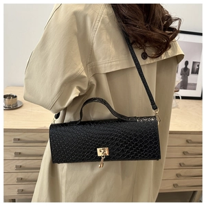 Detail of black woven shoulder bag with gold clasp shown on a beige trench coat