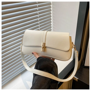 Détail d'un sac baguette blanc crème avec boucle en métal doré et texture mate fine