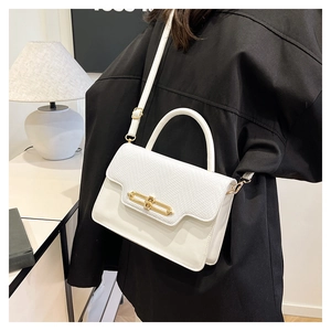 White handbag with lizard texture flap and gold metal turn lock on black blazer