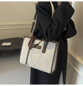 Détail du sac cabas en toile montrant la garniture en cuir et la bandoulière réglable