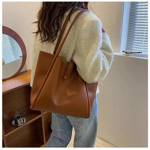 Brown leather tote bag featuring a minimalist buckle closure and spacious interior design