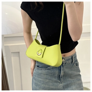 Lime green leather underarm bag with metal buckle shown on a model in a minimalist setting