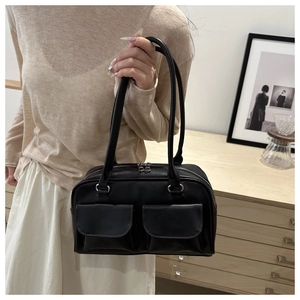 Dettaglio della borsa baguette nera minimalista con doppie tasche e cerniere metalliche