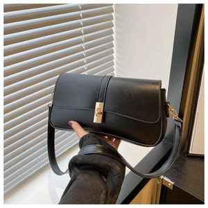 Détail d'un sac à bandoulière en similicuir noir avec fermoir doré rotatif et rabat chic