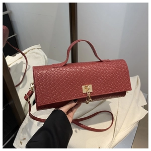 Detailed texture of burgundy woven crossbody bag with gold hardware and shoulder strap