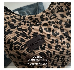 Detail of leopard print corduroy tote bag featuring leather patch and metal zipper closure