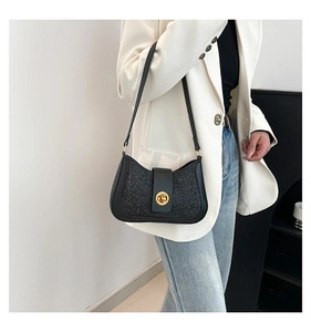 Close-up of black sequin underarm bag with gold metal twist lock on white blazer