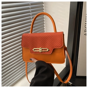 Detail view of bright orange square bag featuring woven texture and gold metal buckle