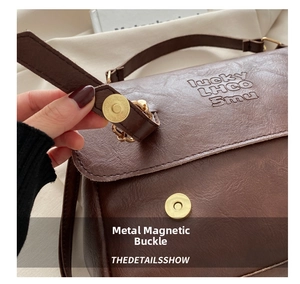 Close-up of golden magnetic snap button on dark brown leather crossbody handbag