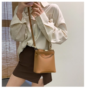 Detail der kamelfarbenen PU-Leder Eimertasche mit FASHION-Logo am Modell getragen
