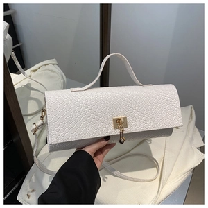 Close-up of woven white leather texture and elegant gold metal clasp on a small square bag