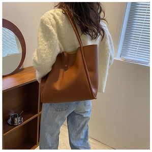 Detailed view of the brown faux leather tote bag being worn in a bright natural setting