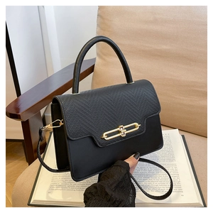 Detail of black crossbody bag with lizard pattern flap and elegant gold metal buckle