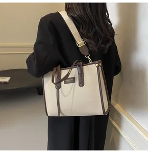 Vue latérale d'un sac cabas en toile beige avec garniture en cuir porté par un mannequin