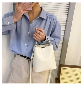 Nahaufnahme der FASHION-Prägung auf einer weißen Kunstleder-Eimertasche für Damen