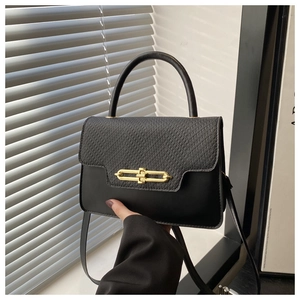 Close-up of black crossbody bag with mixed textures and gold bar metal lock detail