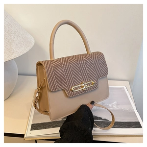 Close-up of vintage beige handbag with herringbone pattern flap and gold clasp