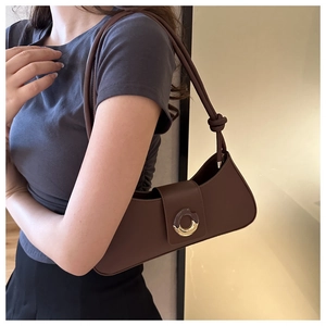 Close-up of a brown crescent-shaped shoulder bag with a gold metal ring buckle detail