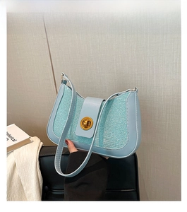 Close-up of light blue shoulder bag with sequin weaving and gold twist lock clasp