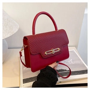 Detail of red leather crossbody bag featuring herringbone textured flap and gold metal buckle