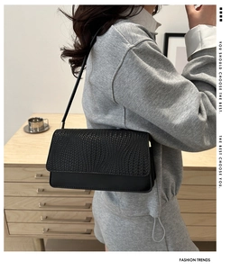 Detail of minimalist black leather baguette bag featuring geometric embossed texture on the flap