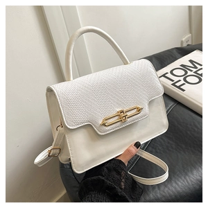 Detail showing the white envelope bag with woven texture, metal lock, and top handle