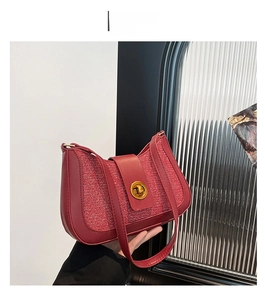 Detail of red glitter shoulder bag featuring a gold rotary lock and leather strap