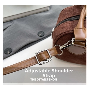 Detail of brown suede bowling bag with adjustable leather strap and metal hardware
