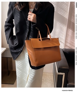 Brown leather tote bag styled with a black blazer featuring soft window light shadows