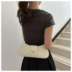 Detail of white minimalist leather crescent shoulder bag with round metal magnetic buckle
