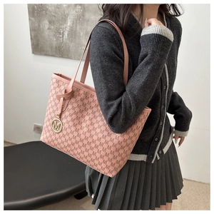 Detail of pink monogram tote bag featuring iconic golden M pendant and leather handles