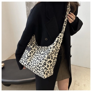 Detail of fashion label on leopard print corduroy tote bag worn with black wool coat