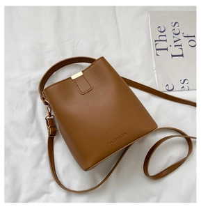 Detail einer braunen Eimertasche aus Leder mit FASHION-Prägung und Metallbeschlägen