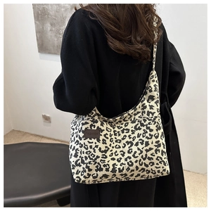 Detail of leopard print corduroy tote bag with brown leather label and slim shoulder strap