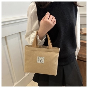 Detail of cute bear patch and love text on brown canvas tote bag for students
