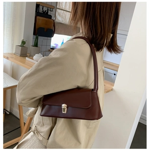 Détail du sac baguette vintage bordeaux avec boucle en métal doré sur l'épaule